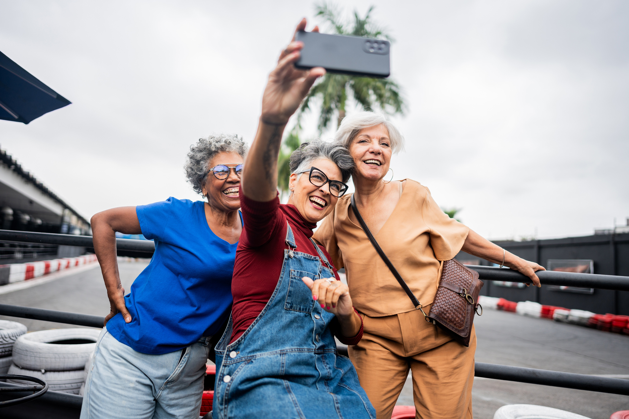 Three older women pose together for a selfie, having fun together. They look happy to spending time with one another and remaining active.